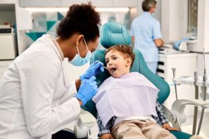 A dental hygienist cleaning an adult patient's teeth in a bright, modern dental office.